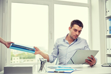 businessman taking papers from secretary in office