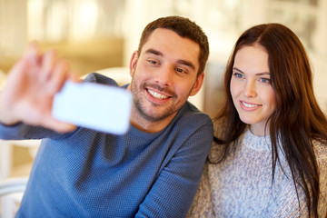 couple taking smartphone selfie at cafe restaurant