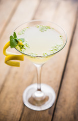Yellow martini cocktail with lemon and mint on the rustic wooden background. Shallow depth of field.