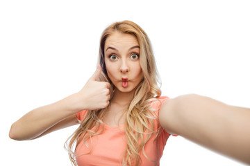 young woman taking selfie and showing thumbs up