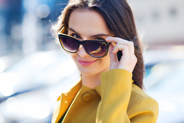 smiling young woman with sunglasses in city