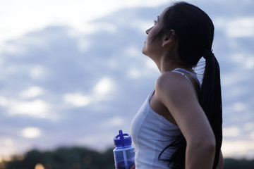 Woman jogger drinking water from shaker after workout training