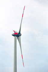 Closeup of generator windmill blades on blue sky background. Windmill generator in wide yard.Large metal blade with red lines.