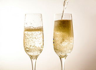 Two glass of champagne wine close up, bubbles, on a softlight background
