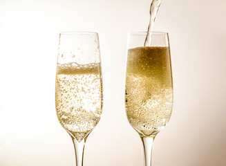 Two glass of champagne wine close up, bubbles, on a softlight background
