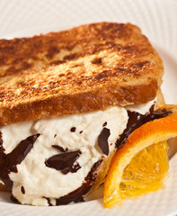 Baked French Toast with Ricotta and Chocolate with a slice of orange on a white plate