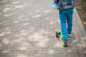 Child on a Scooter. Feet of a kid boy with sneakers on scooter on a sunny day.  child riding scooter outdoors, active sport kids