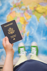 Child's hand holding US passport. Map background. Ready for traveling. Open world.