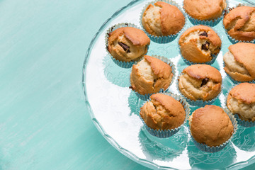 Delicious homemade vanilla muffins with chocolate on the glass plate on turquoise background. Sweet dessert for celebration, party or snack. Cupcakes.