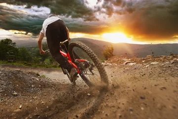  Man on mountain bike rides on the trail on a stormy sunset. © KopoPhoto