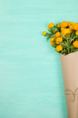 Bouquet of yellow flowers on turquoise wooden background. Top view on birthday bouquet. Flay lay. Lifestyle and holidays concept.