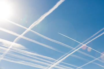 Airplanes in blue sky with Vapor Trail. Condensation trails of planes in the sky. Vertical and horizontal lines in the sky like chessboard or cellular field. Peace. Aviation. Travel concept.