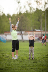 Obraz premium Happy mother and son on the stadium enjoying their sport activities. Family doing exercises outdoors and greeting winners. Fitness, healthy lifestyle, together concept.
