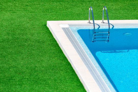 Swimming pool with stair in hotel pool resort.Swimming pool with blue spa swimming pool with clean water.Beautiful swimming pool with green grass around.