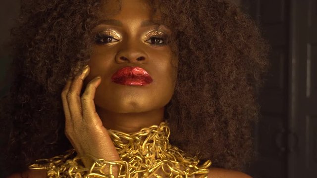 Surreal Fashion Portrait of African American Female Model with Golden Glossy Headwear. Creativity concept, black studio background
