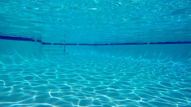 Underwater view of sunlight patterns in empty swimming pool.