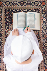 Little Muslim kid reading Quran in Ramadan