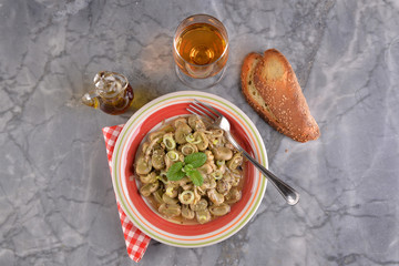 Dish of broad beans stewed with onion and oregano and mint on the marble table
