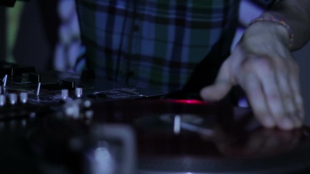 DJ scratching vinyl records and mixing on the Decks at a disco in Nightclub 15