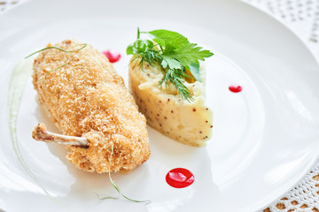 Chicken Kiev fried in breadcrumbs, Parmesan sauce and mashed potatoes with Dijon mustard served on a white plate