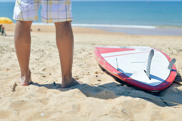 Obraz premium Closeup on surfer legs with surfing board ocean beach background