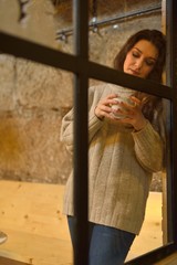 attractive young woman drinking coffee behind a window