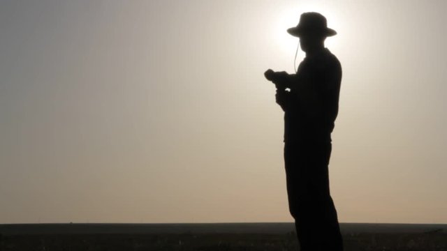 Silhouette of a cowboy shooting a pistol on a background of the rising sun
