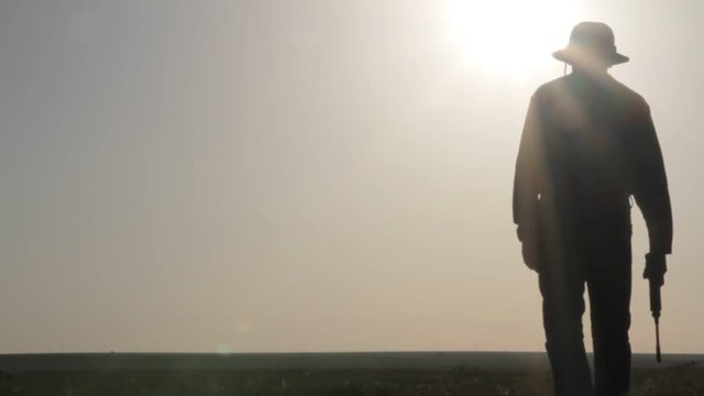 Silhouette of a cowboy shooting a pistol on a background of the rising sun
