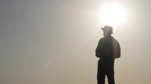 Silhouette of a cowboy shooting a pistol on a background of the rising sun
