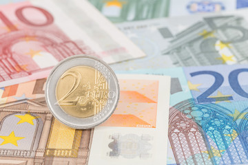 Two euro coin stand on banknote money