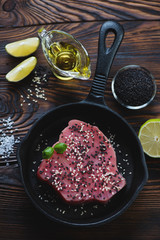 Top view of a frying pan with raw tuna steak in sesame seeds