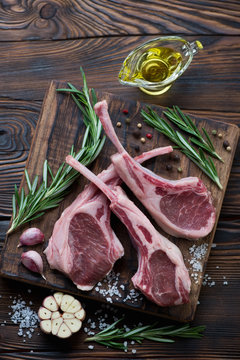 Fresh uncooked lamb chops with condiments, rustic wooden setting