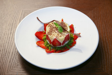 layered dessert with strawberries, biscuit cake and cream cheese on a dark wood background
