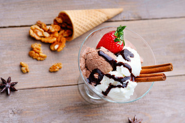 Ice cream sundae, waffle cone, walnuts and strawberry on a table