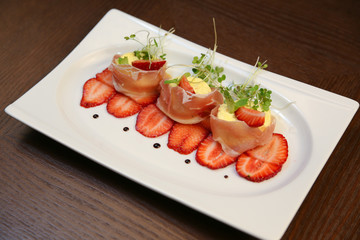 layered dessert with strawberries, biscuit cake and cream cheese on a dark wood background