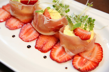 layered dessert with strawberries, biscuit cake and cream cheese on a dark wood background