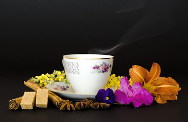  tazza di tisana calda,contornata dai fiori e dalle spezie