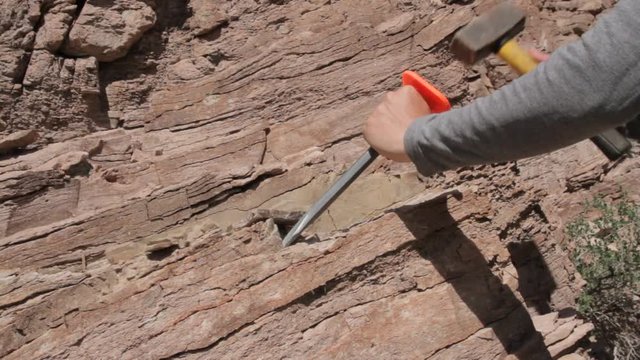 man destroys the rock with a hammer and chisel
