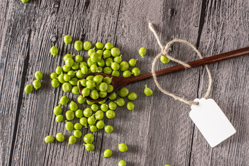 peas on a wood table with spoon and tag