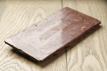 whole homemade bar of chocolate with cashew nuts, on wooden board shalow focus
