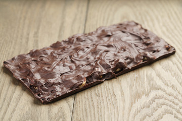 whole homemade bar of chocolate with cashew nuts reverse side, on wooden board shalow focus