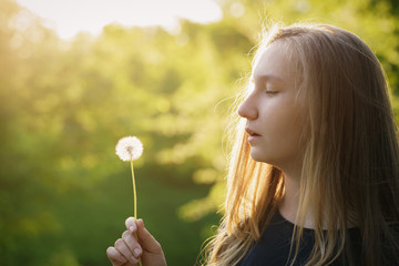 teen girl ready to blow dandelion, side view