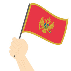 Hand holding and raising the national flag of Montenegro