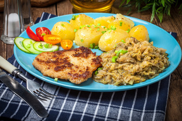 Fried pork chop, baked potatoes and fried young cabbage.