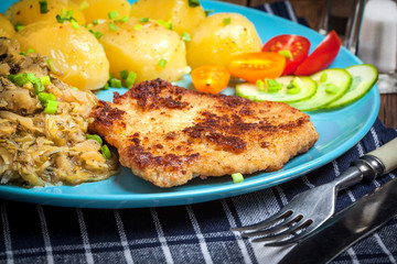 Fried pork chop, baked potatoes and fried young cabbage.
