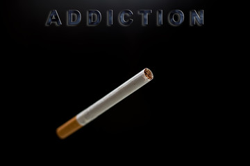 cigarette, text addiction on black background