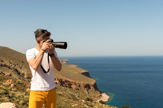 man taking a picture of the landscape against the sea