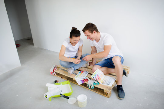 The young couple selects color for coloring of walls in the new apartment.
