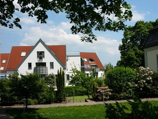 Blick über eine schöne grüne Gartenanlage auf ein modernes Mehrfamilienhaus mit spitzem Giebel im Sonnenschein in Oerlinghausen bei Bielefeld am Hermannsweg im Teutoburger Wald in Ostwestfalen-Lippe