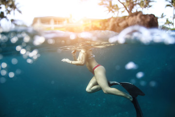 Sexy woman with a beautiful figure floating in the ocean. Photos under water in the sun